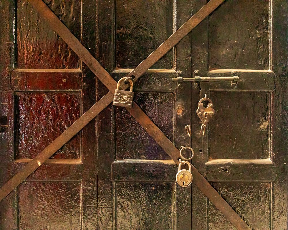 Close-up of wooden door with multiple padlocks.